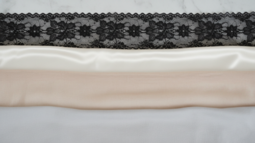 Lingerie Fabric Textures Fabric samples of lace, satin, mesh, and cotton on white marble.